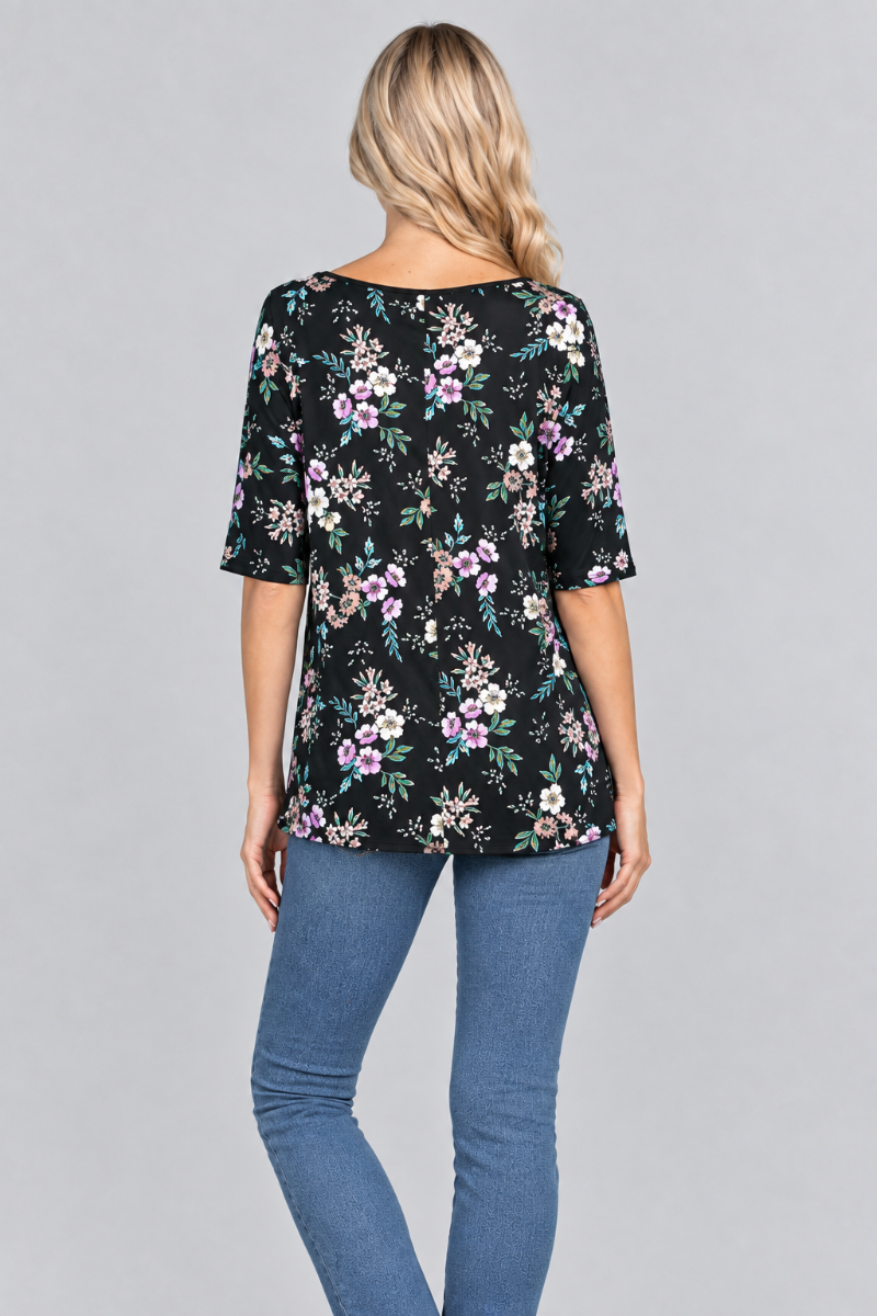 Back studio view of the blonde model wearing the black floral top and denim jeans