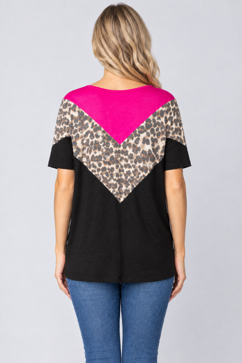 Back studio view of the blonde model wearing the black top with fuchsia and leopard-print chevrons and blue jeans