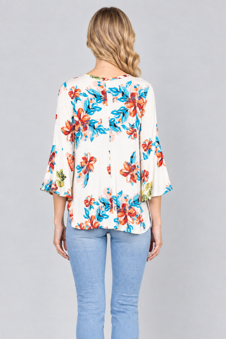 Back studio view of the blonde model wearing the ivory floral blouse and light-wash jeans