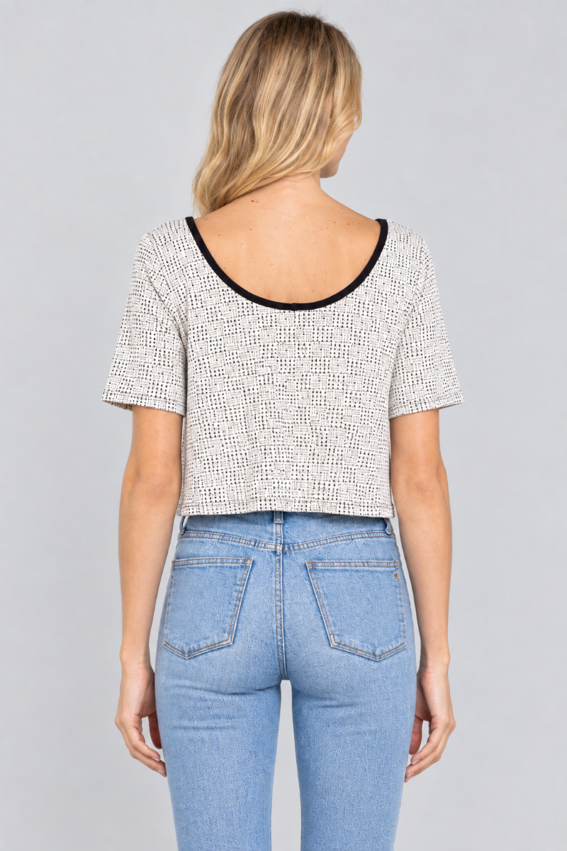 Back studio view of the blonde model wearing the ivory micro-print top and light-wash jeans