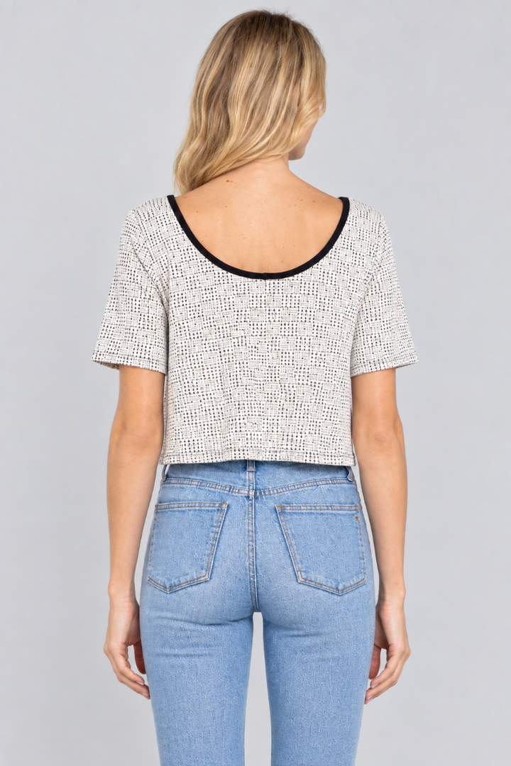 Back studio view of the blonde model wearing the ivory micro-print top and light-wash jeans