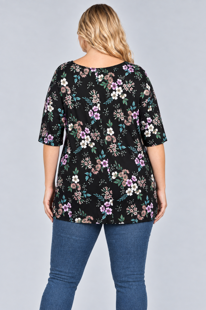 Back studio view of the blonde plus-size model wearing the black floral tunic and blue jeans
