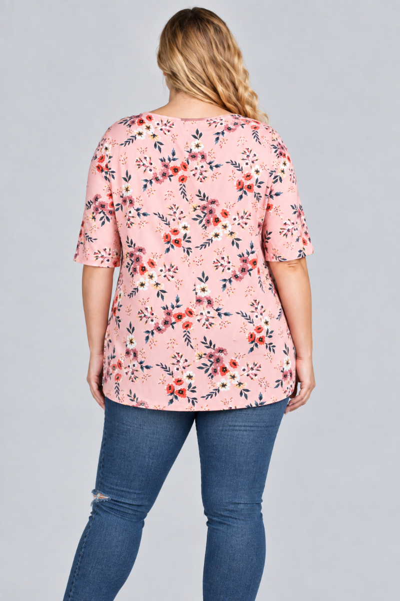 Back studio view of the blonde plus-size model wearing the blush-pink floral tunic and blue jeans