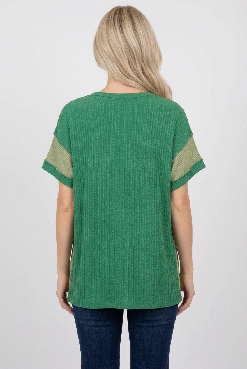 Back view of the blonde model wearing the green top and dark jeans