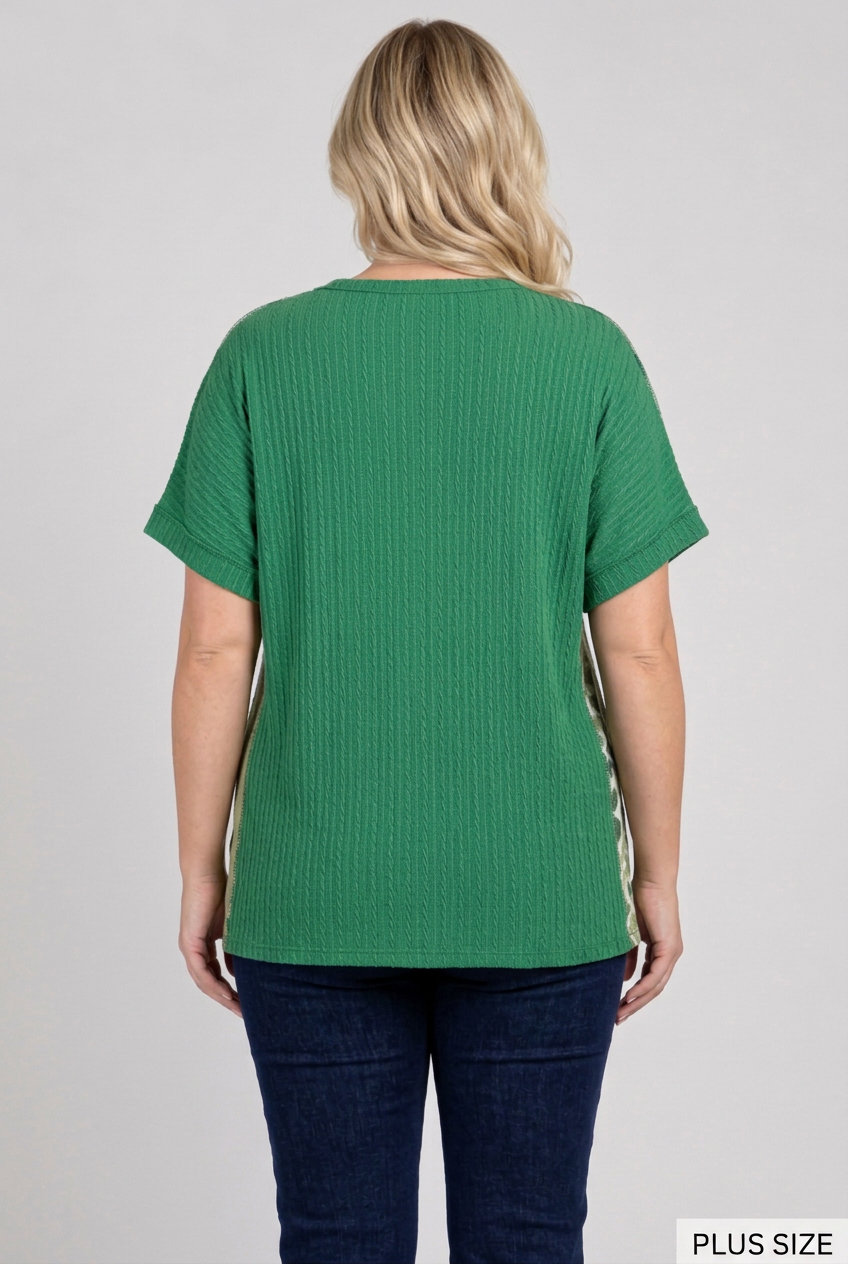 Back view of the plus-size blonde model wearing the green top and dark pants