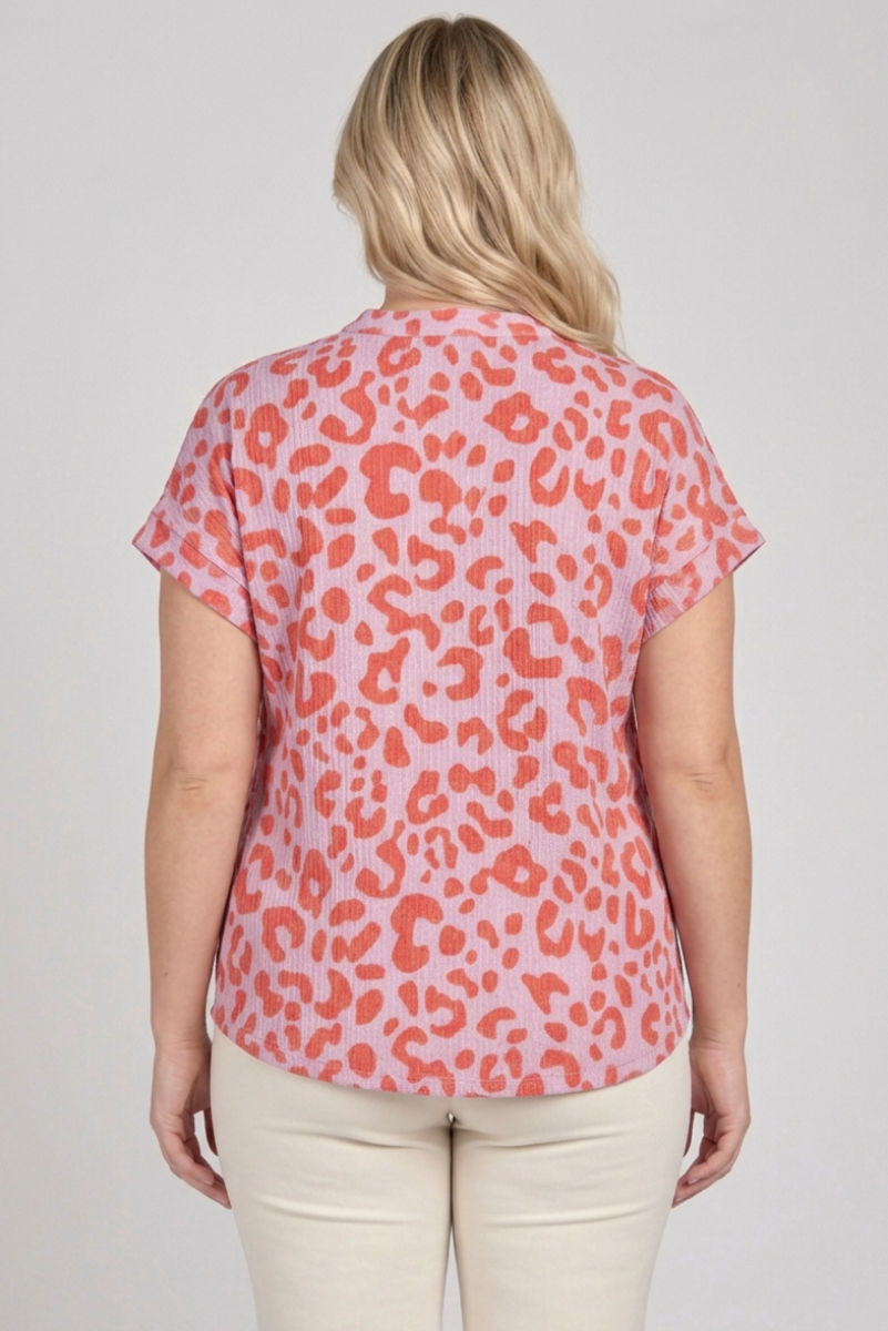 Back view of the plus-size blonde model wearing the pink and coral top with cream pants