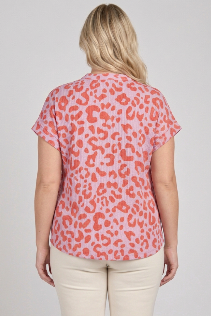 Back view of the plus-size blonde model wearing the pink and coral top with cream pants