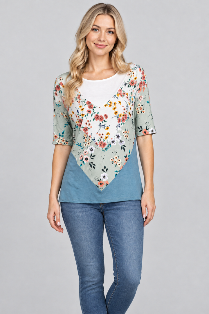 Blonde model wearing the sage floral and teal top with medium-blue denim jeans