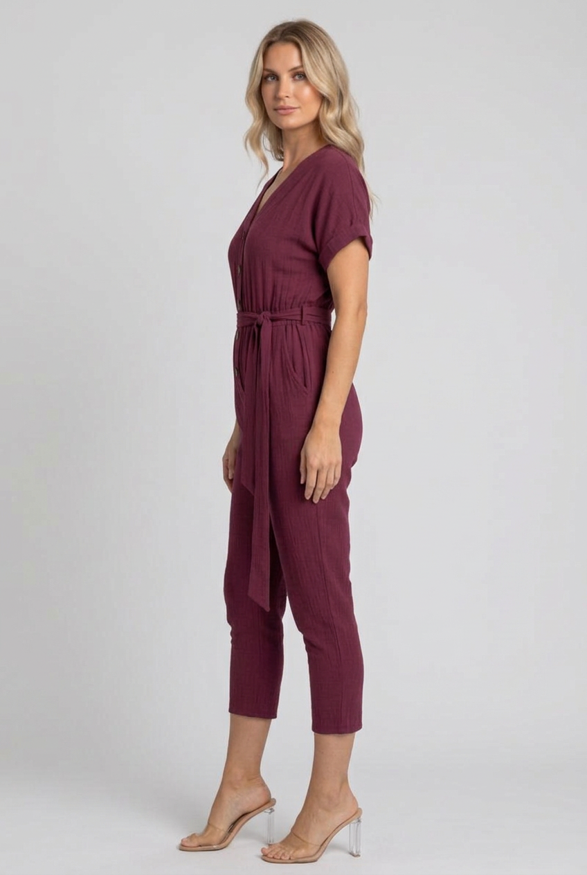 Clear side studio view of the burgundy jumpsuit with face toward camera