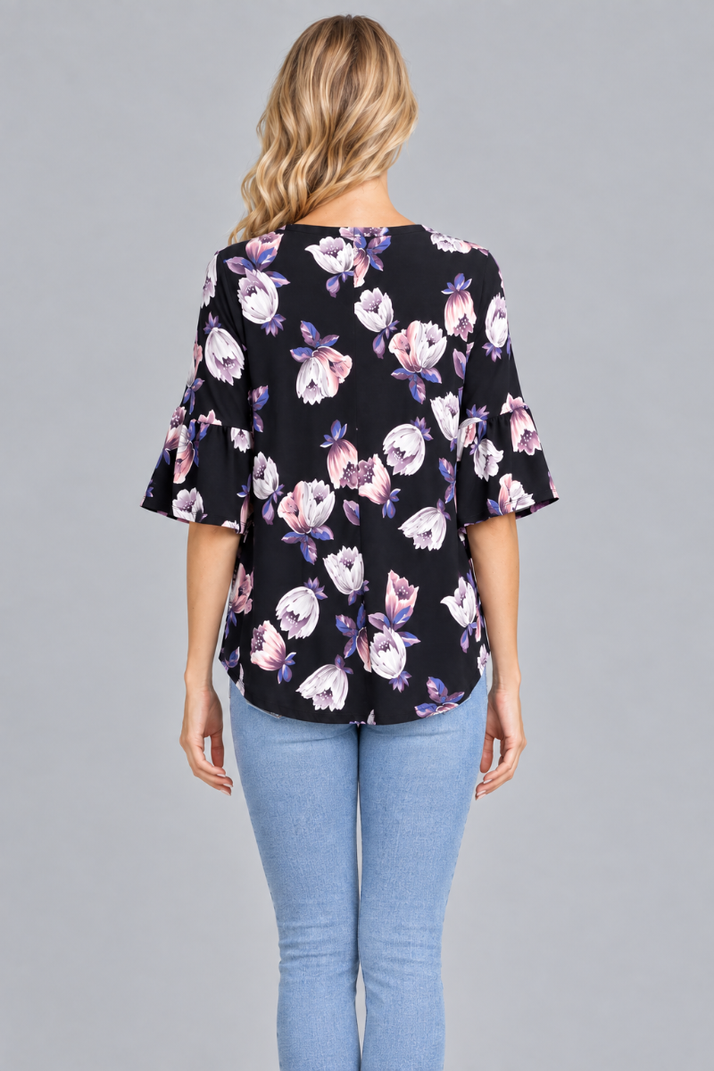 Full-back studio view of the blonde model wearing the black floral blouse and light-wash jeans