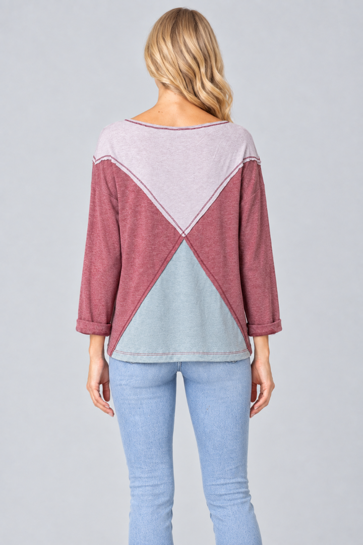 Full-back studio view of the blonde model wearing the lilac, mauve, and pale-blue geometric top