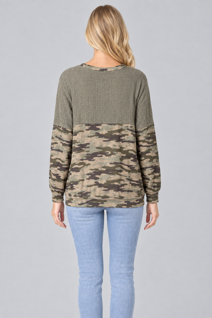 Full-back studio view of the blonde model wearing the olive and camouflage color-block top with light-wash jeans