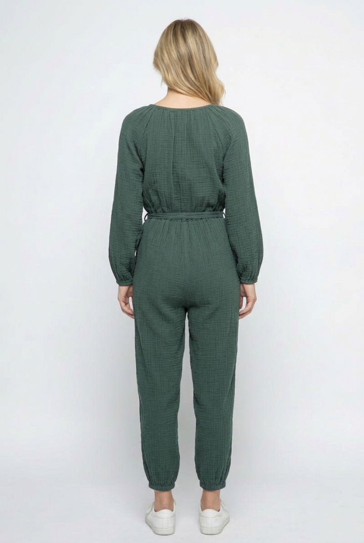 Full-back studio view of the forest-green jumpsuit with white sneakers