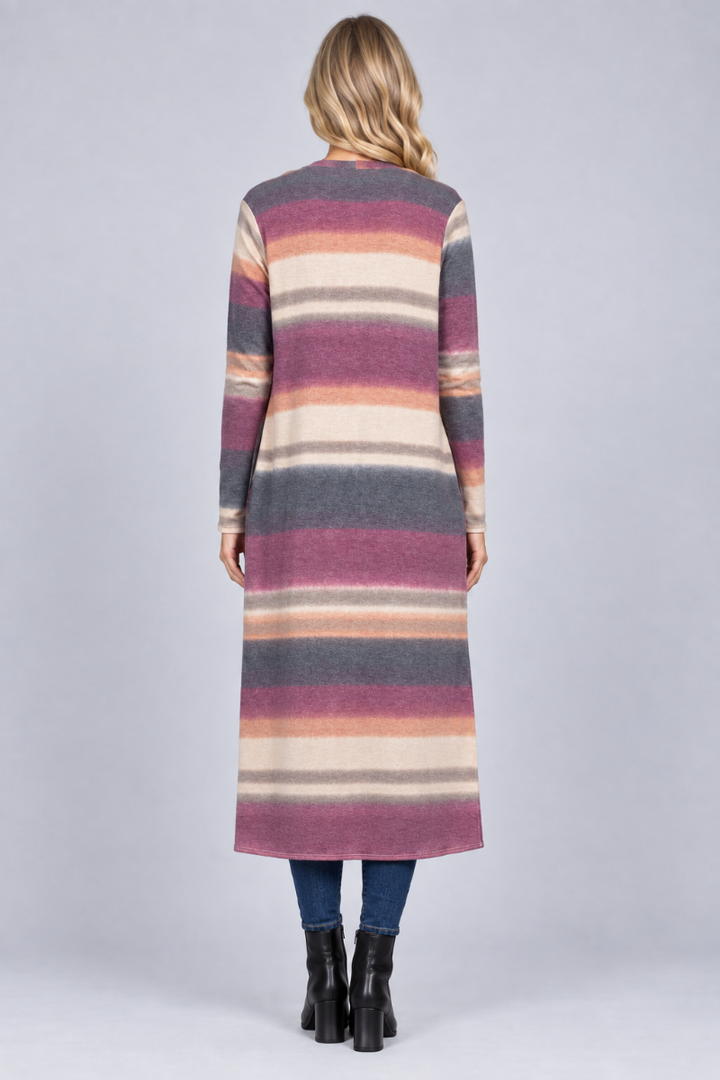 Full-body back studio view of a blonde model wearing the long striped cardigan, jeans, and black boots
