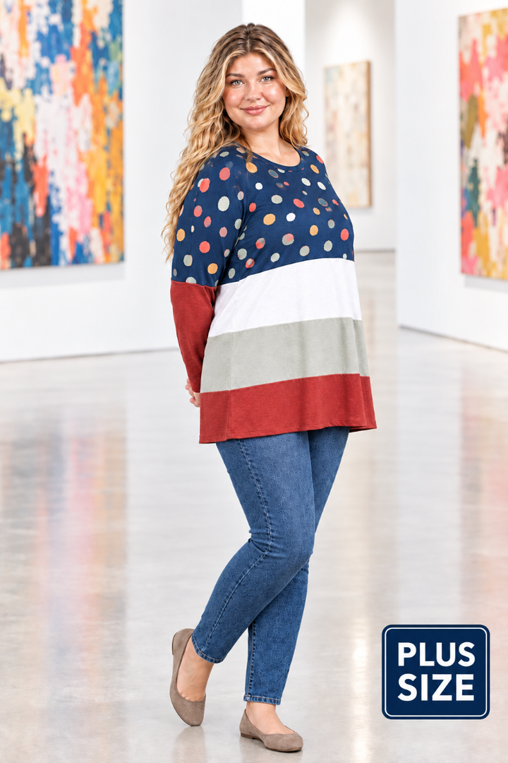 Full-body half-side view of blonde model in navy dotted color-block tunic and blue jeans in a modern art gallery