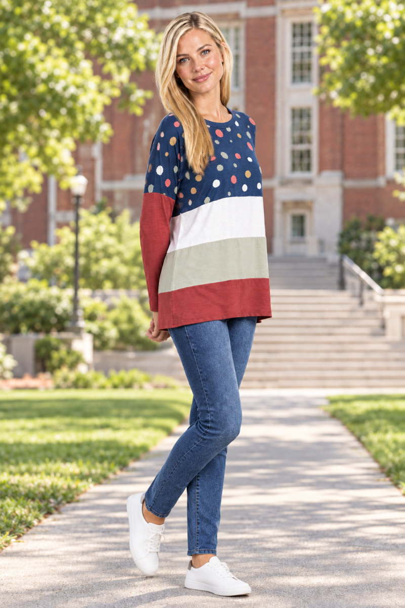 Full-body half-side view of blonde model in navy dotted color-block tunic and jeans on a university campus quad