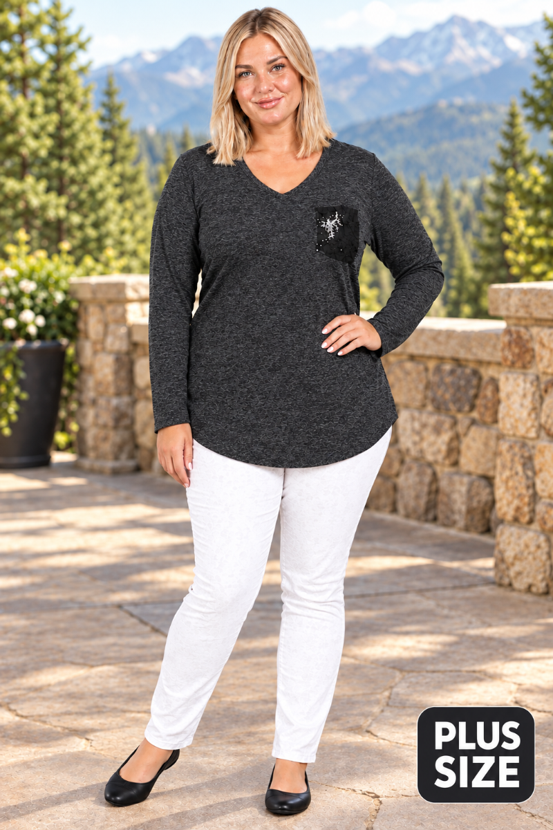Full-body lifestyle front view of blonde model in charcoal heather tunic with black pocket detail, white pants, and black flats on a mountain-lodge terrace