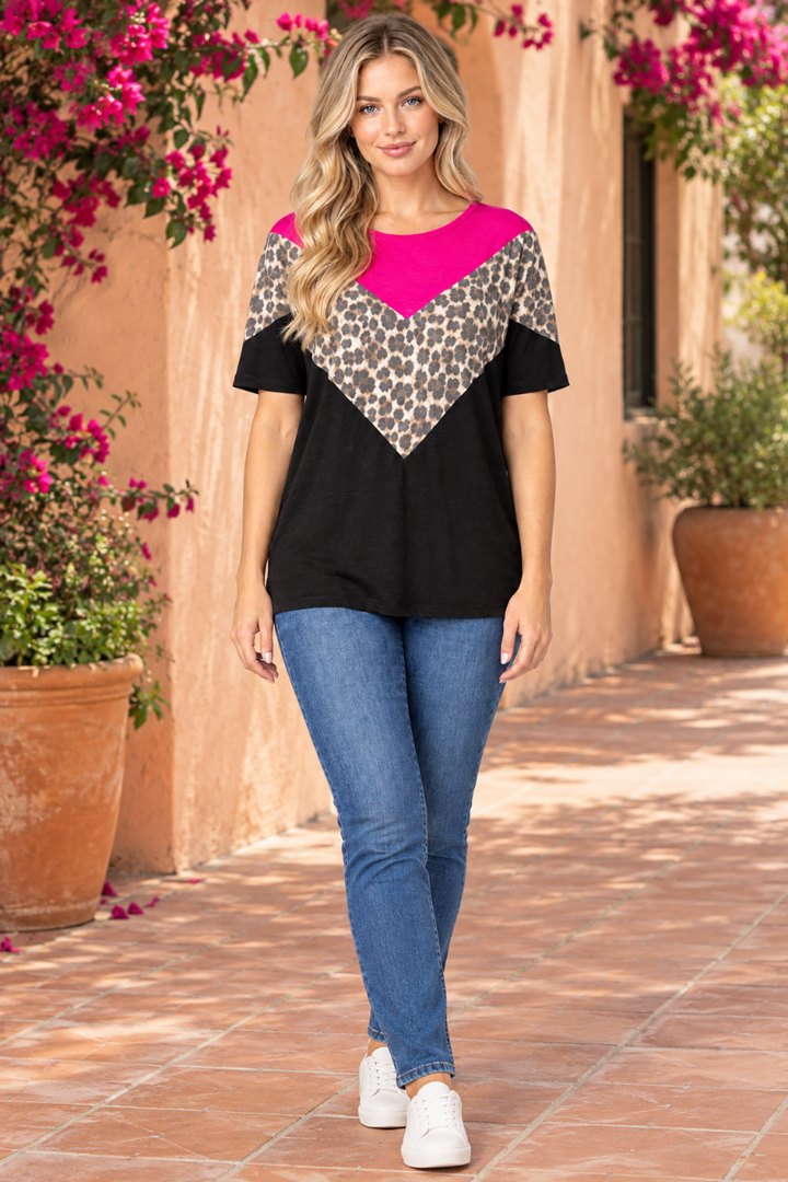 Full-body lifestyle front view of the blonde model wearing the black, fuchsia, and leopard-print top with blue jeans
