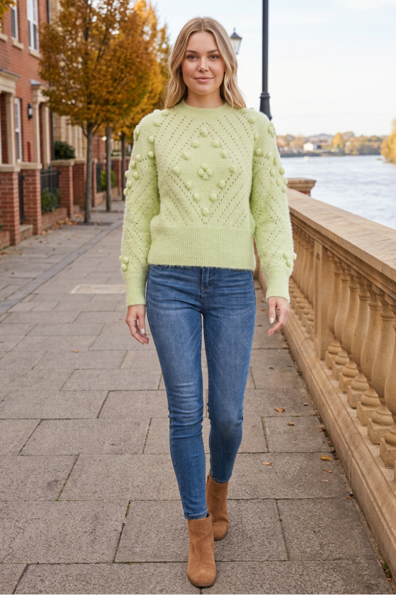 Full-body lifestyle front view wearing the pale green sweater in an autumn riverside setting
