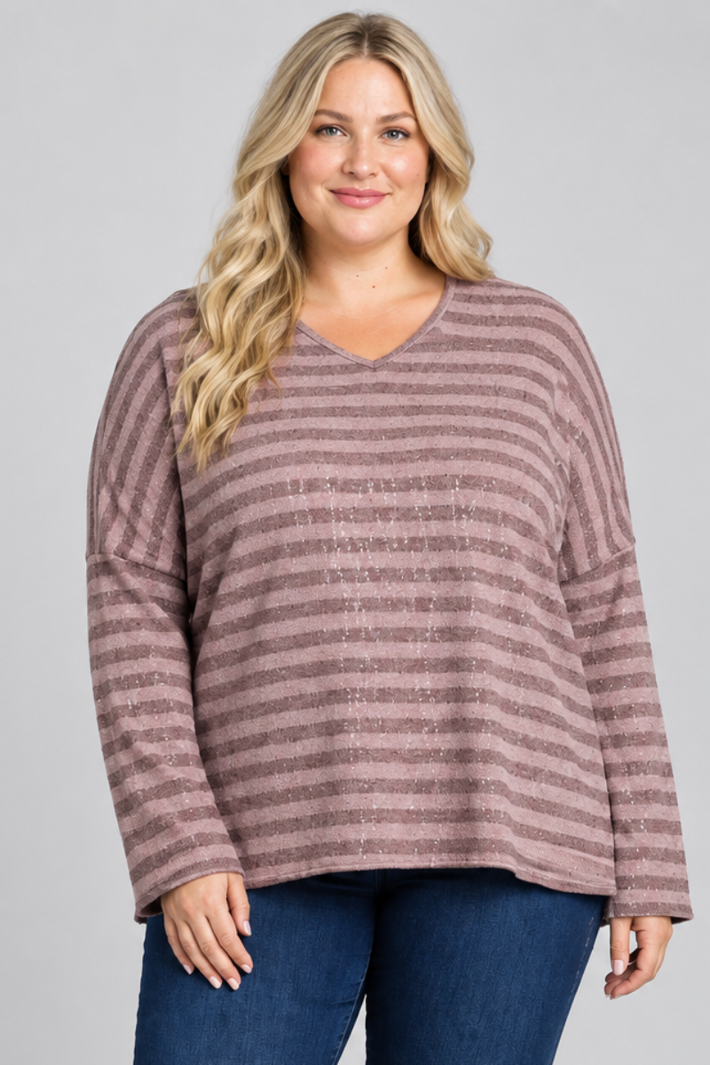Full-body studio front view, blonde plus-size model in mauve striped top and dark jeans