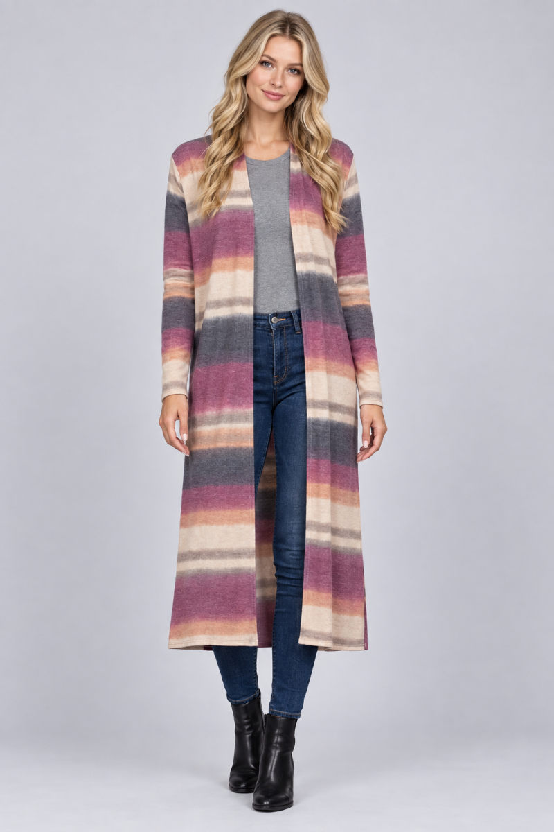 Full-body studio front view of a new blonde model wearing the striped mauve cardigan, gray top, jeans, and black boots