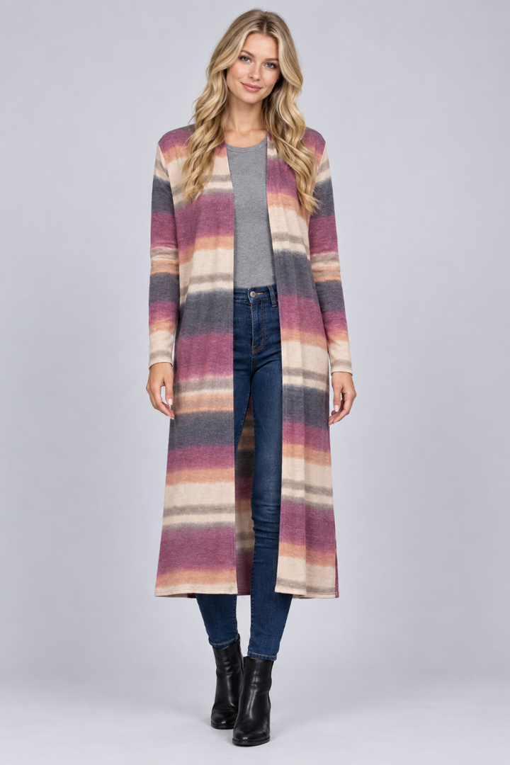 Full-body studio front view of a new blonde model wearing the striped mauve cardigan, gray top, jeans, and black boots