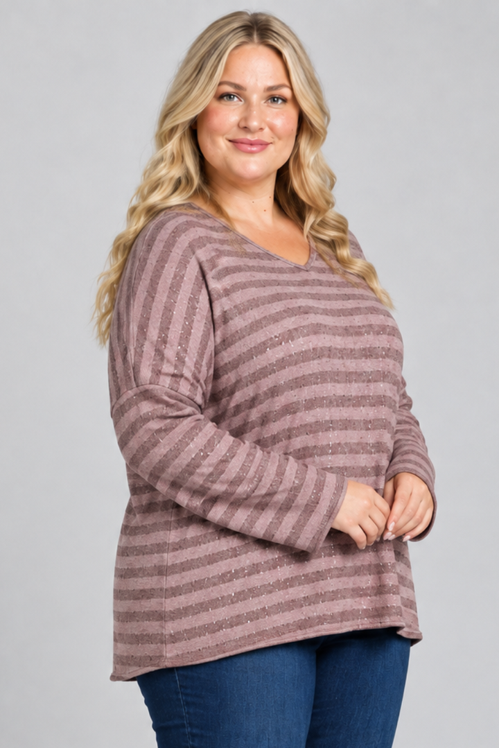 Full-body studio side view, blonde plus-size model in mauve striped top and dark jeans