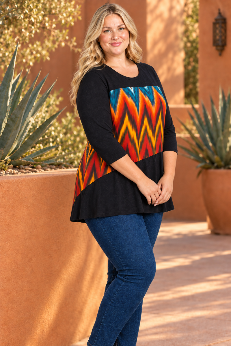 Half-side lifestyle view of blonde model in black tunic with colorful geometric panel, terracotta courtyard