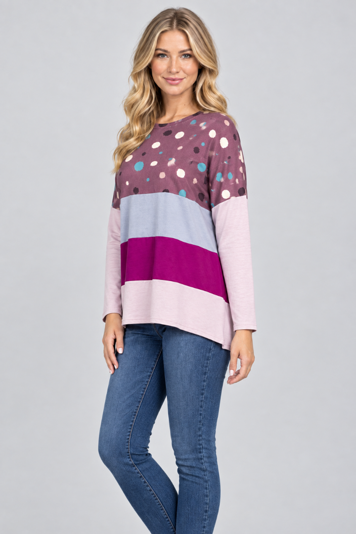Hat-free studio side view of blonde model in plum dotted color-block tunic and jeans