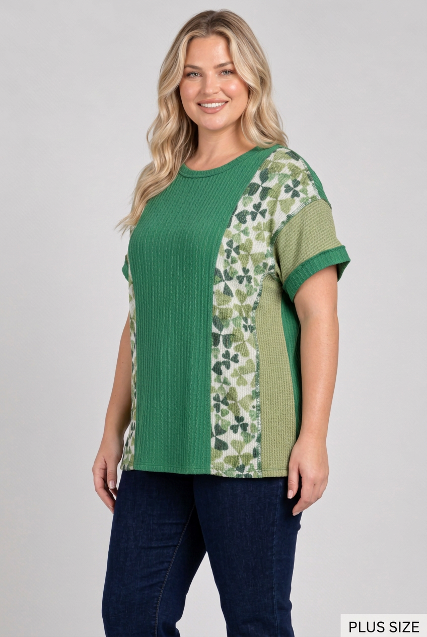 Plus-size blonde model in a side pose wearing the green top and dark pants