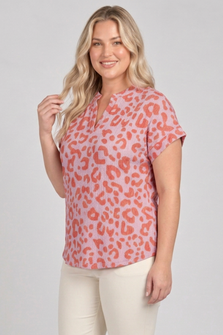 Plus-size blonde model in a side pose wearing the pink and coral top with cream pants