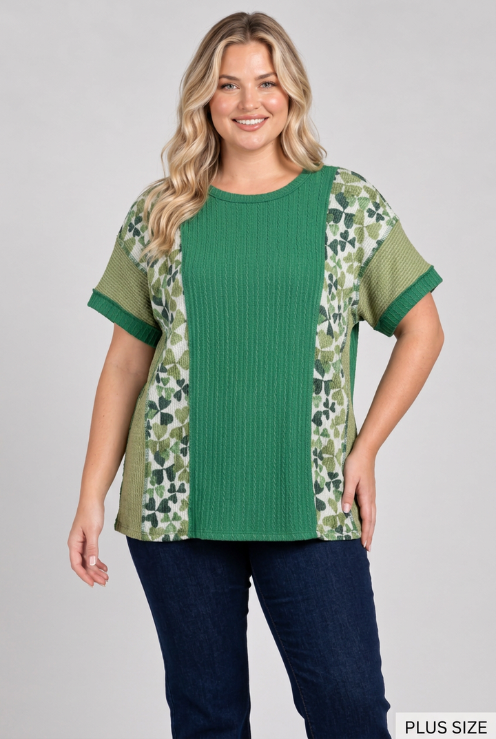 Plus-size blonde model wearing the green butterfly-panel top and dark pants