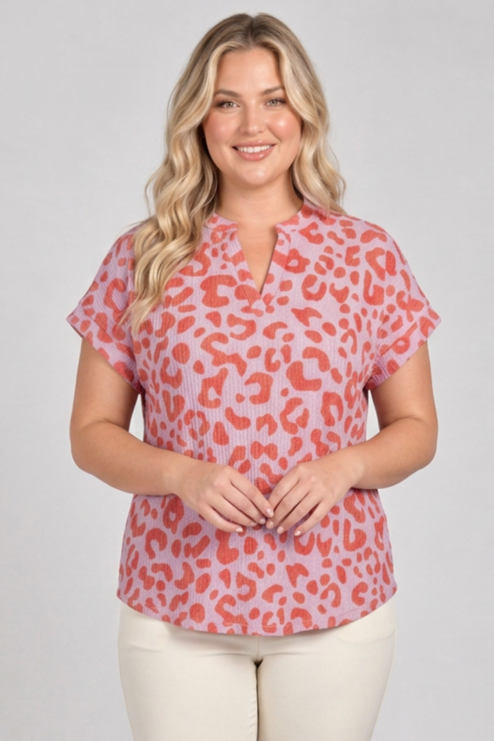 Plus-size blonde model wearing the pink and coral top with cream pants