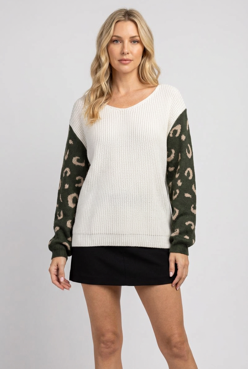 Regular-size blonde model wearing the ivory sweater with olive patterned sleeves and black skirt