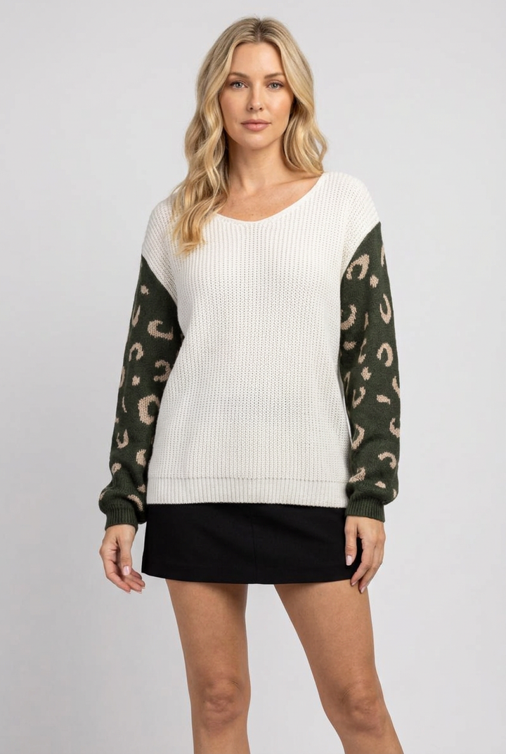Regular-size blonde model wearing the ivory sweater with olive patterned sleeves and black skirt