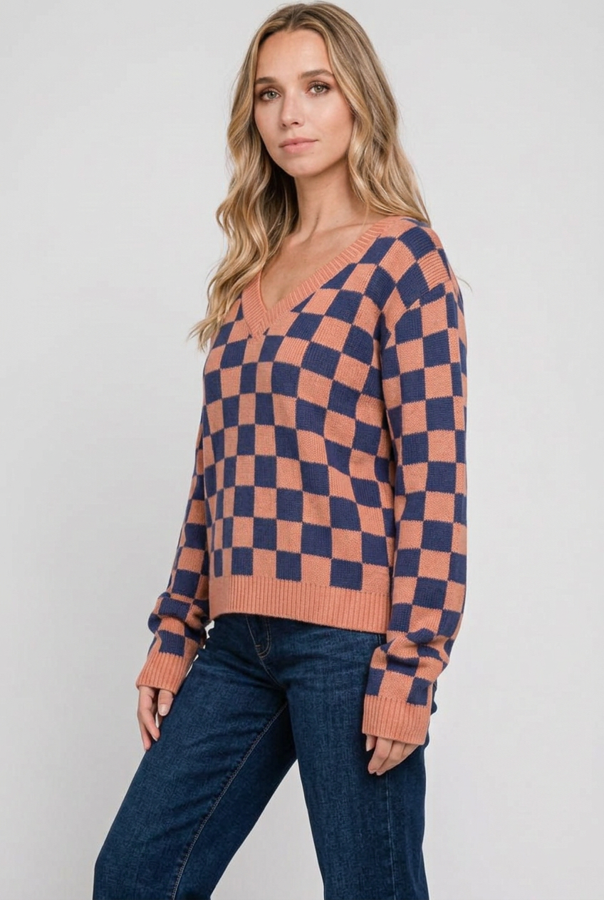 Side studio pose wearing the checkerboard sweater and dark-wash jeans