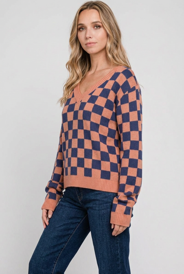 Side studio pose wearing the checkerboard sweater and dark-wash jeans