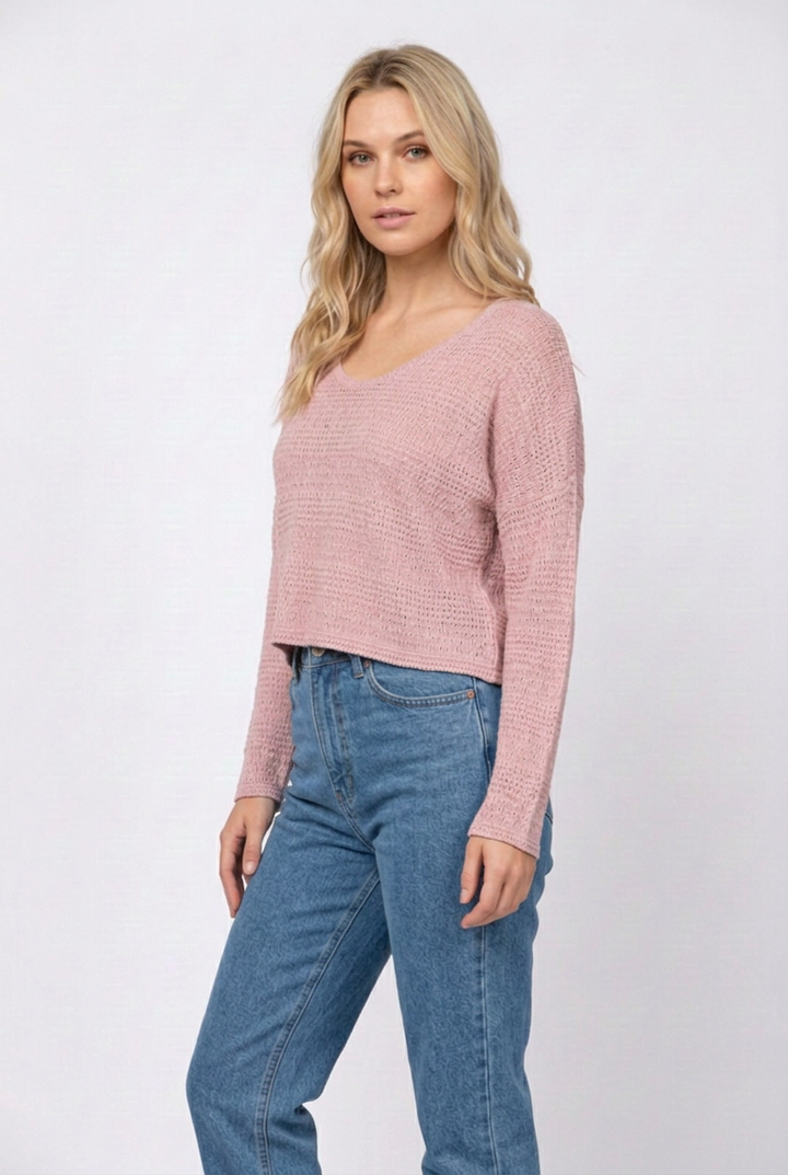 Side studio pose wearing the dusty-pink sweater and denim jeans