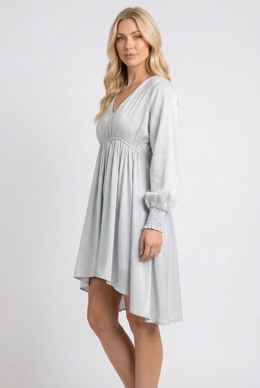 Side studio pose wearing the pale blue-gray flowing dress