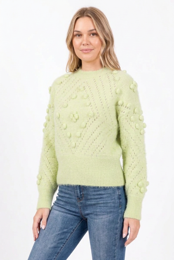 Side studio pose wearing the pale green bobble-knit sweater