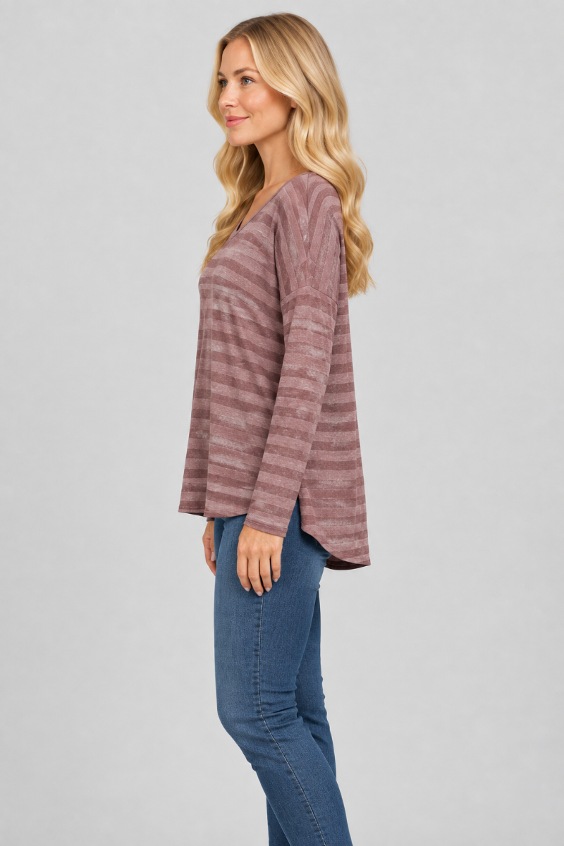 Side studio view of the blonde model wearing the mauve striped top and blue jeans