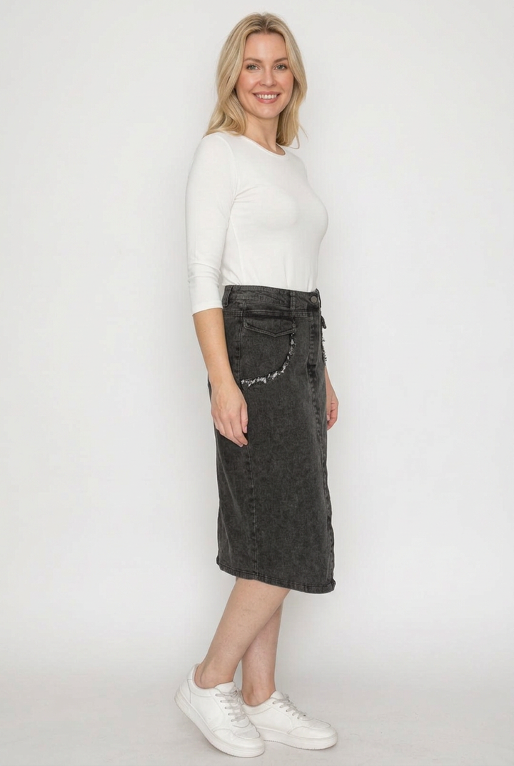 Side studio view with white top and black denim skirt