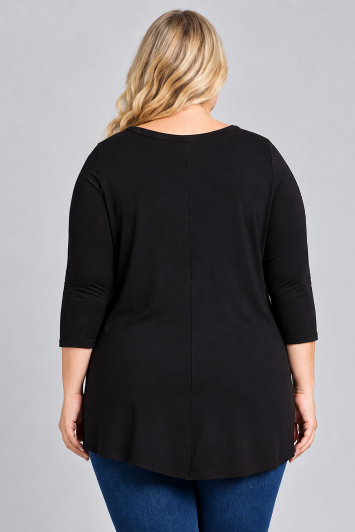 Studio back view of blonde model in black tunic and dark jeans