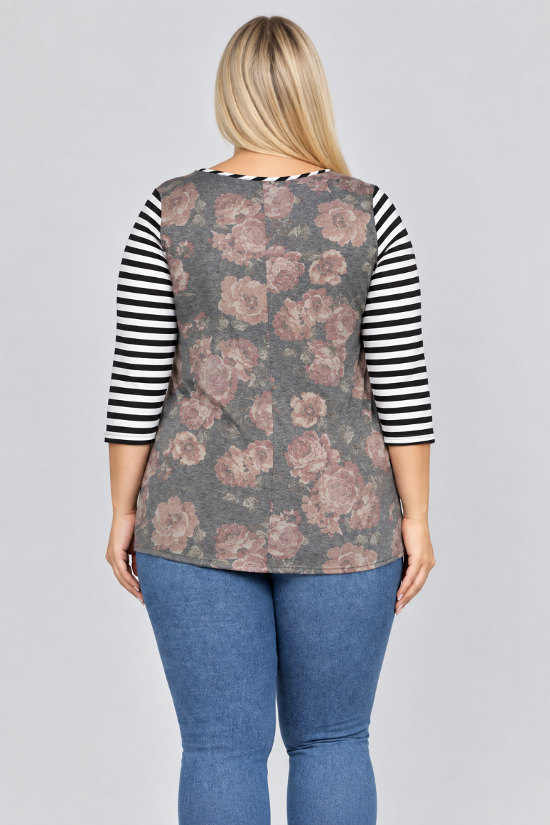 Studio back view of blonde model in charcoal floral top with black-and-white striped sleeves and blue jeans