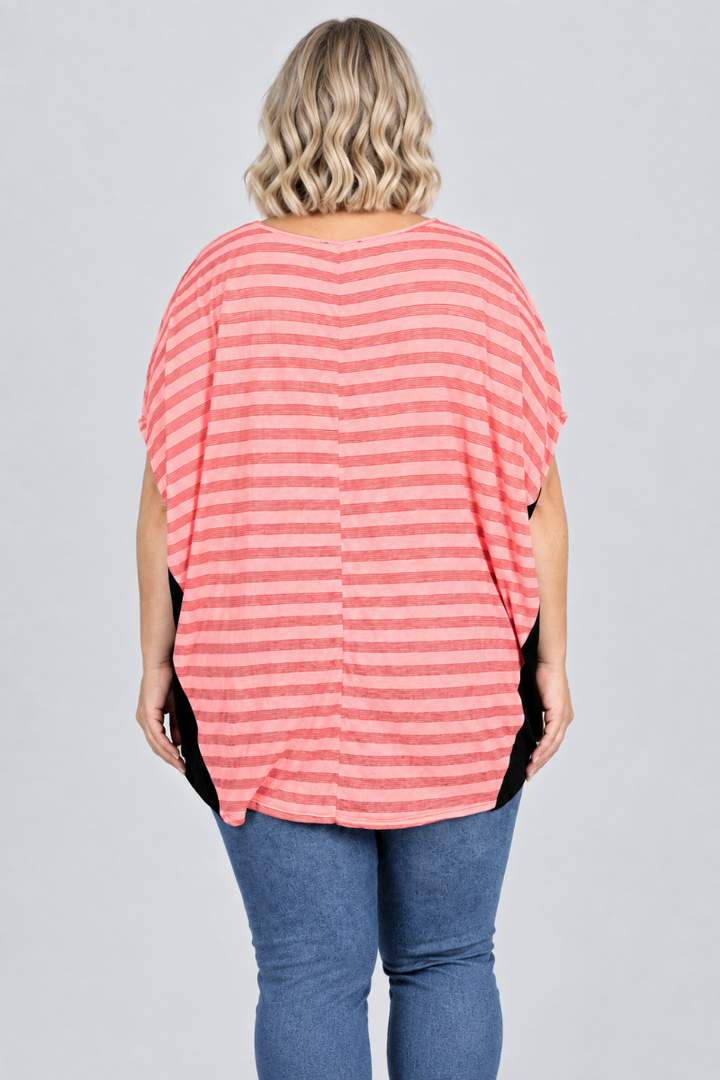Studio back view of new blonde model in pink striped dolman top with black side panels and blue jeans