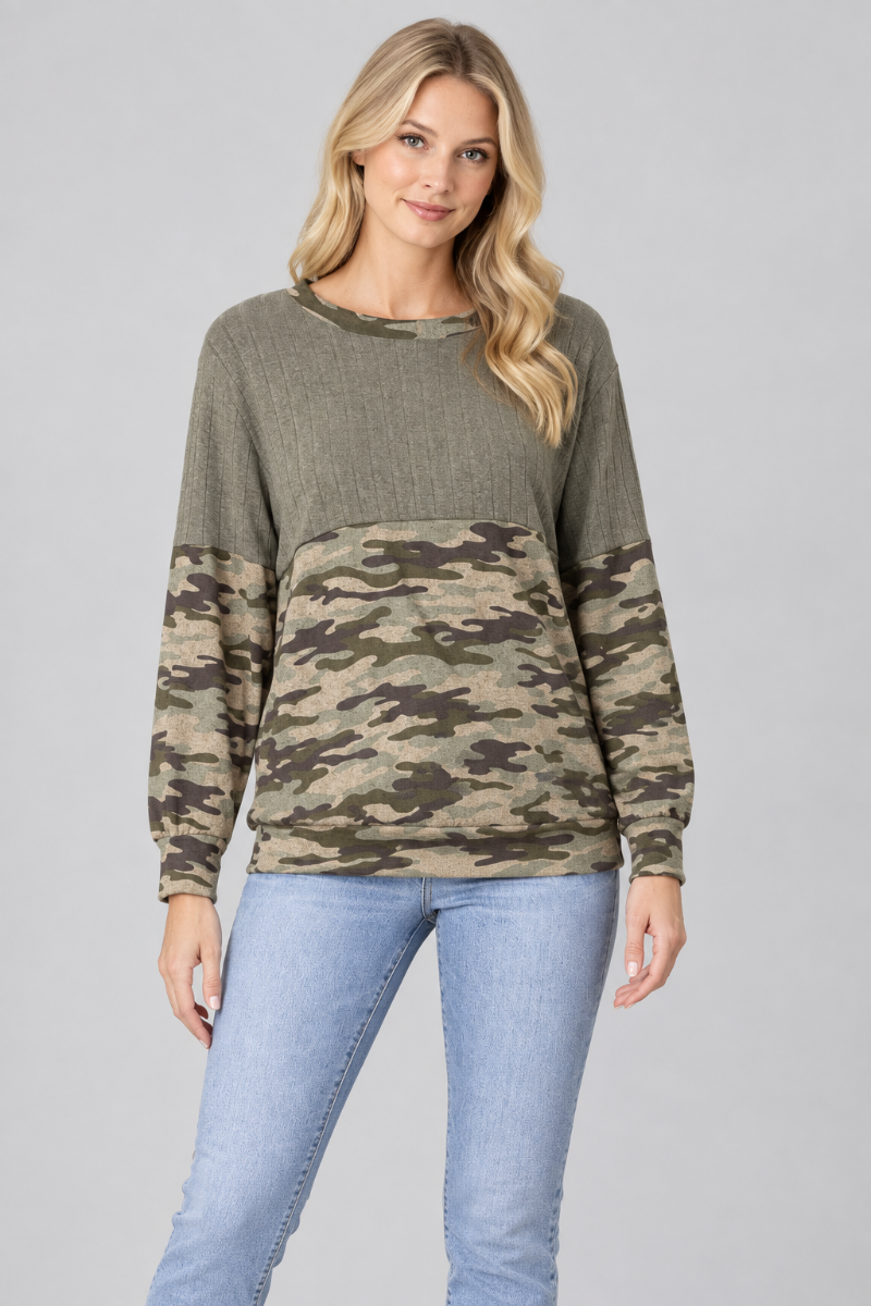 Studio front view of a blonde model wearing the olive and camouflage color-block top with light-wash jeans
