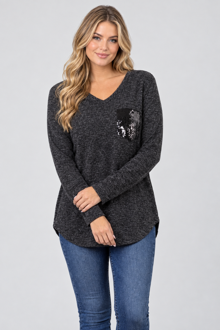 Studio front view of a new blonde model in a charcoal heather V-neck tunic with black embellished pocket and blue jeans