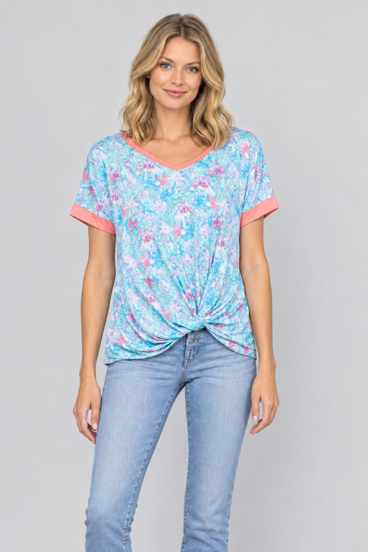 Studio front view of a new blonde model wearing the aqua floral twist-front top and light-wash jeans