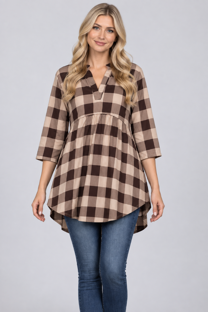 Studio front view of a new blonde model wearing the beige-and-brown plaid tunic and blue jeans