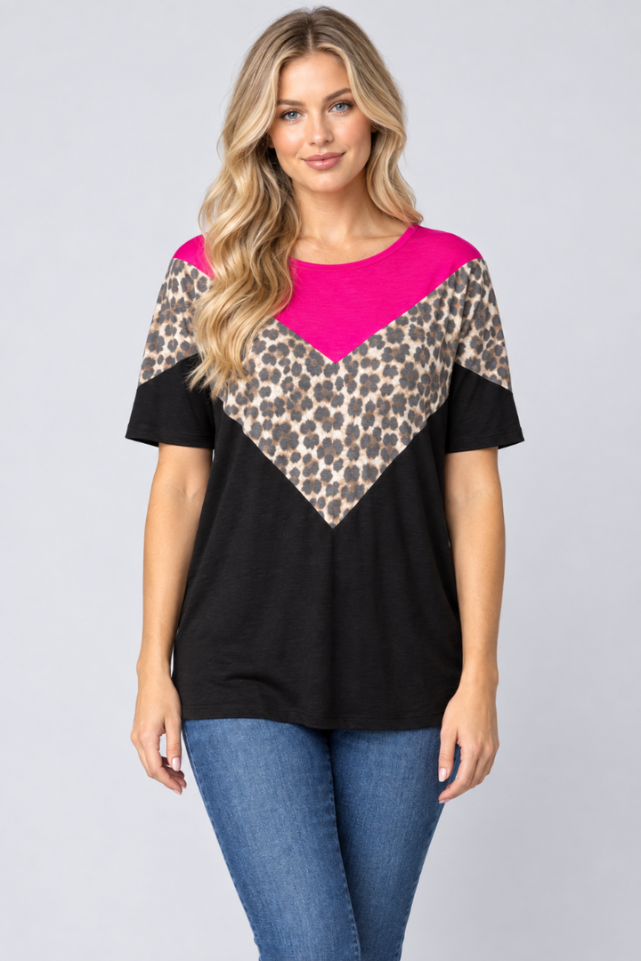 Studio front view of a new blonde model wearing the black, fuchsia, and leopard-print top with blue jeans